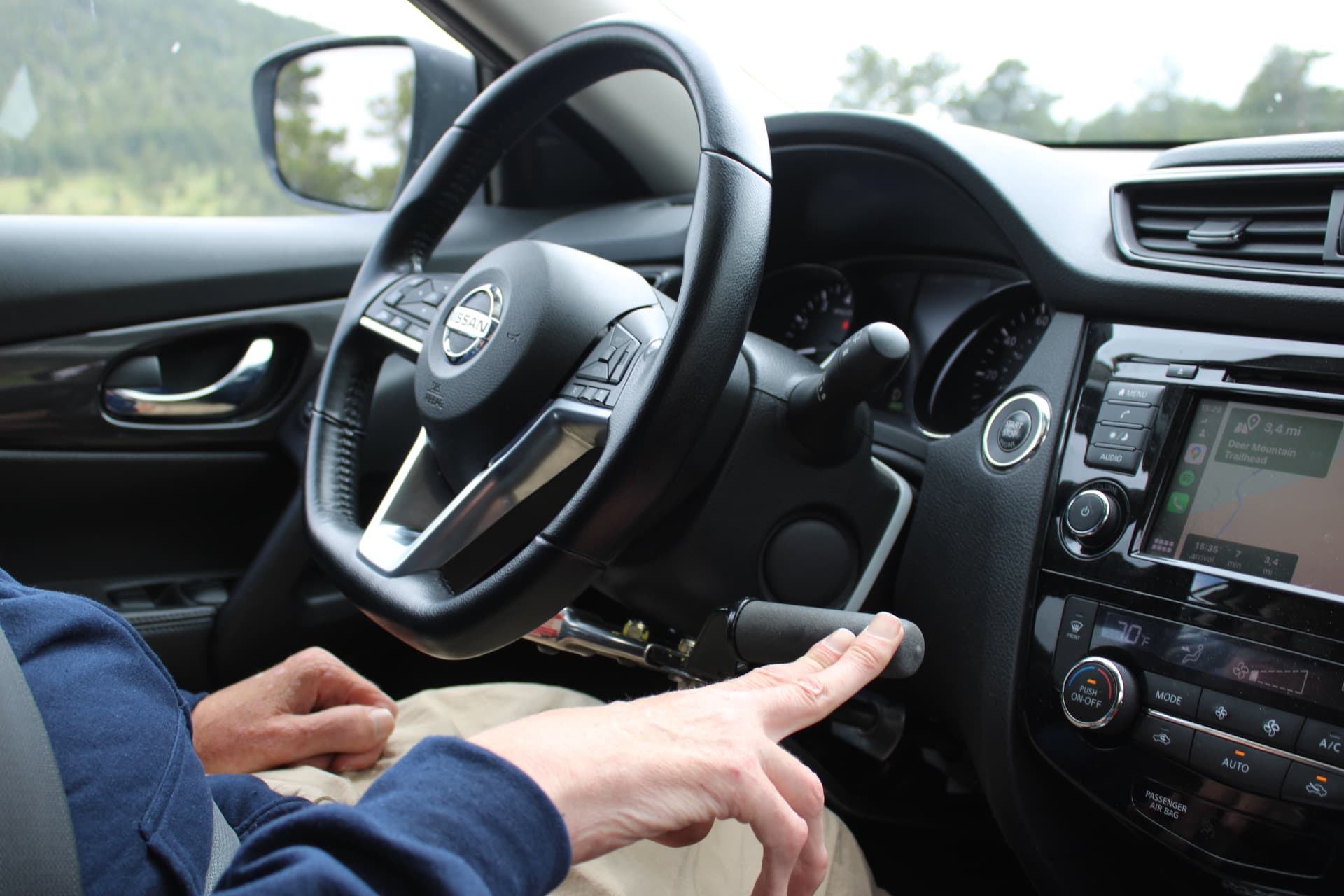 Hand op de handbediening naast het stuur van een Nissan huurauto