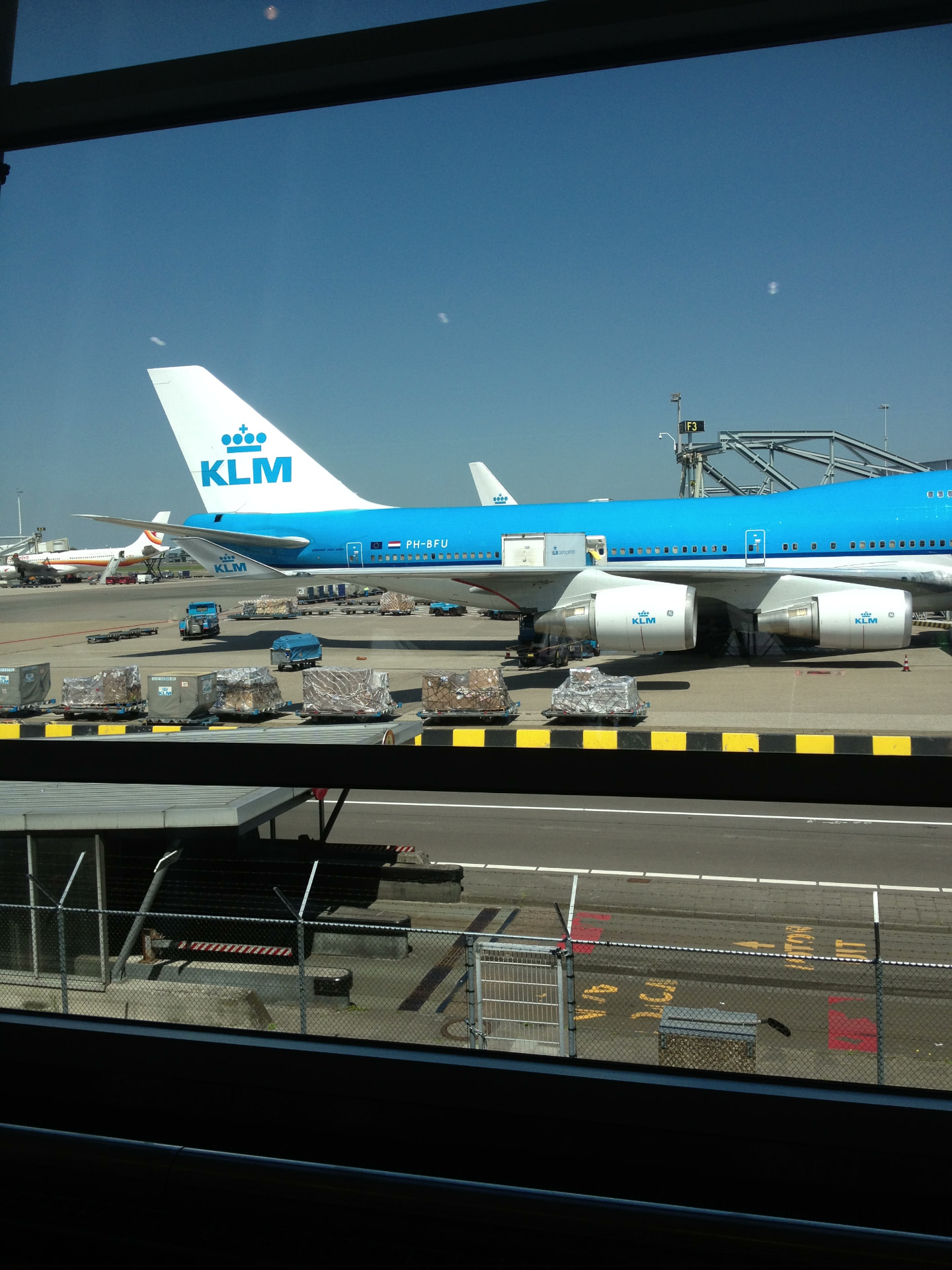 KLM Boeing 747 bij de gate op Schiphol gezien vanuit de vertrekhal