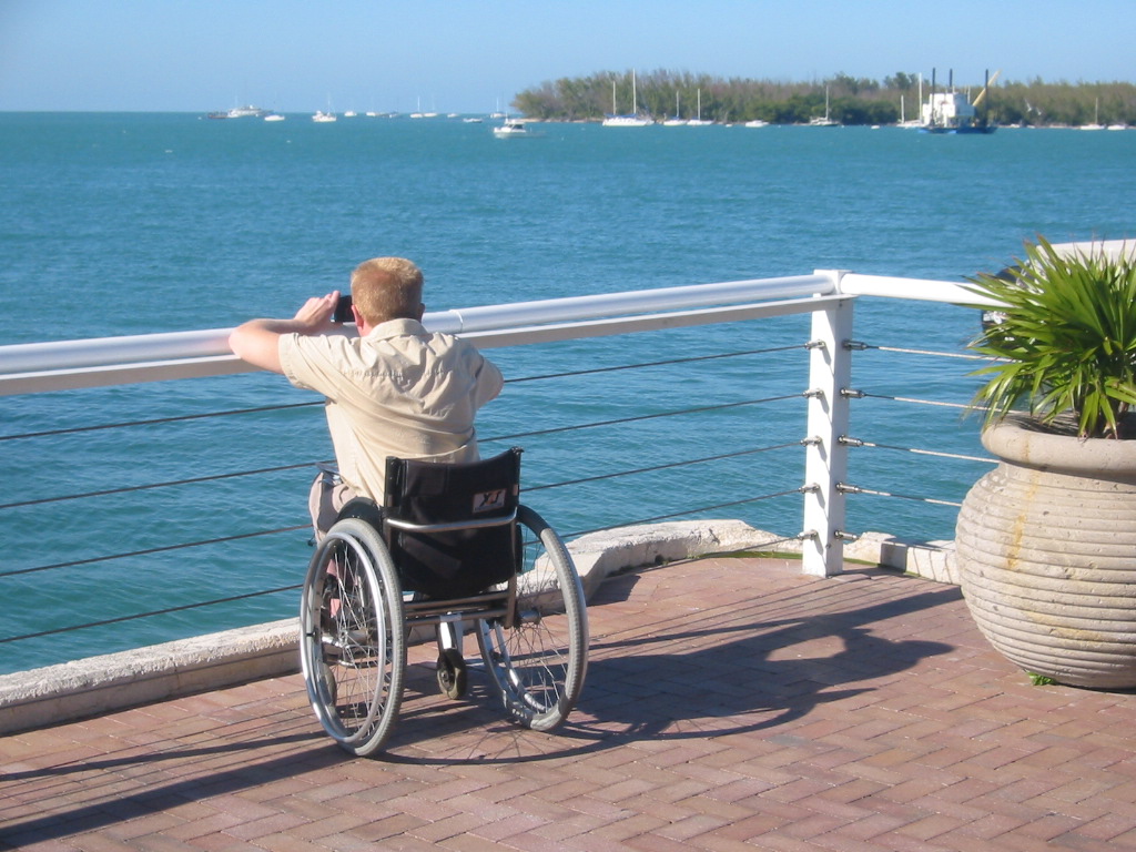 Freek kijkt vanuit de rolstoel over het water bij een toegankelijke kade in Florida